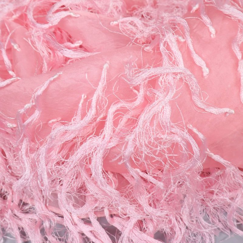 Närbild på rosa sjalens fransiga textur och mjuka material