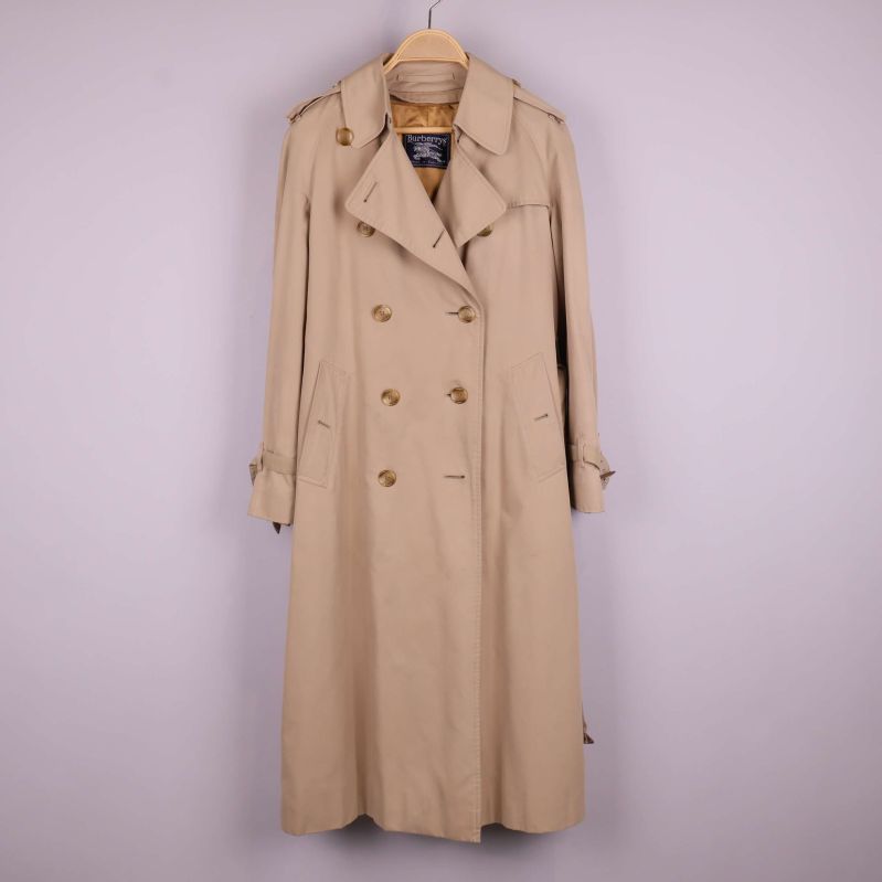 Beige trenchcoat med dubbelknäppning och bälte framifrån