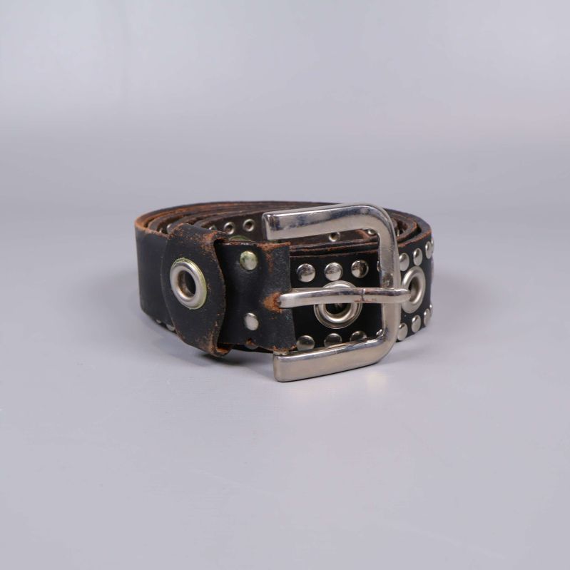 Rullat bälte med nitar och silverdetaljer mot ljus bakgrund