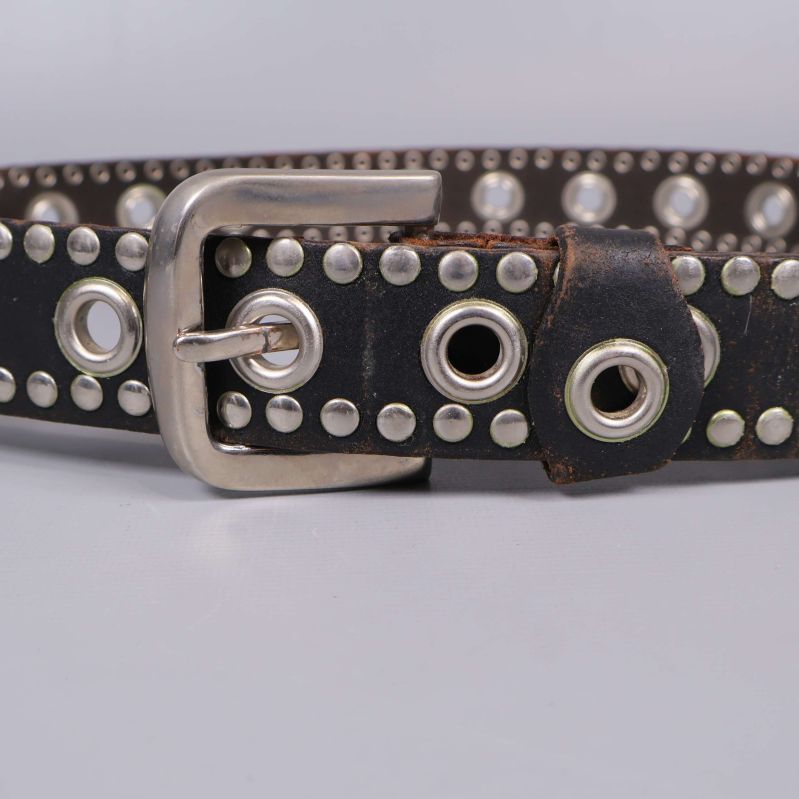 Närbild på bältesspänne och nitar i silver