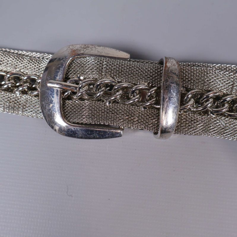 Närbild på silverfärgat spänne och kedja på skärp