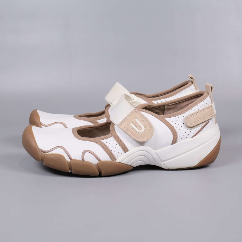 Sida av vit och beige sko med perforering och kraftig sula
