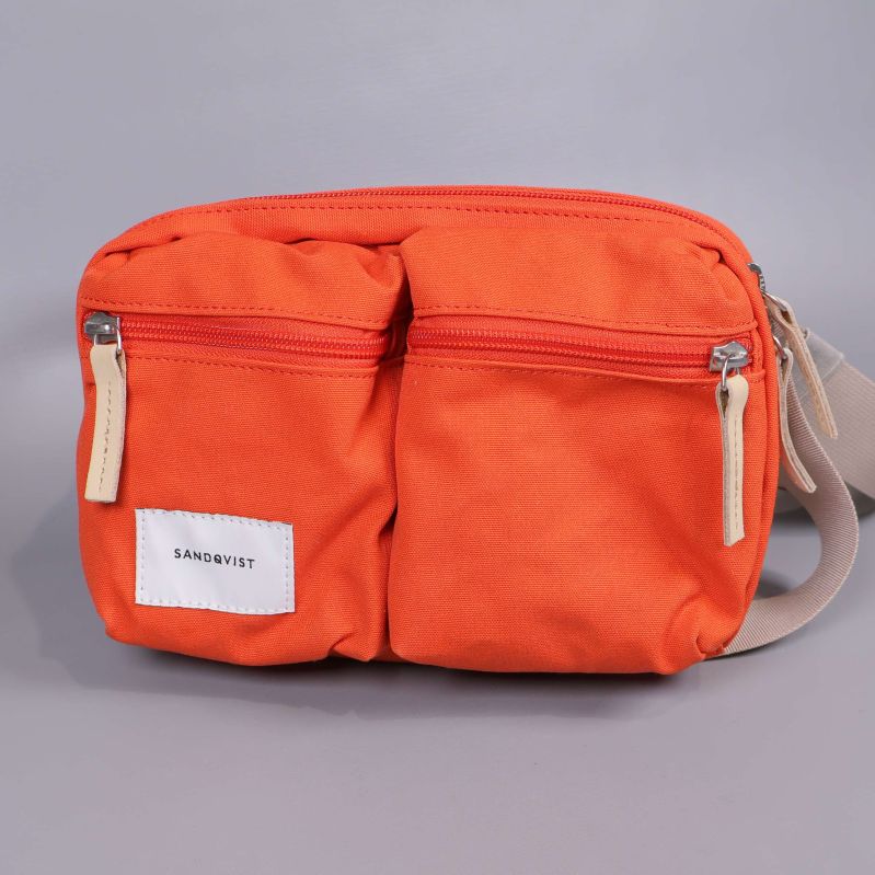 Orange axelväska fotograferad framifrån med dragkedjor
