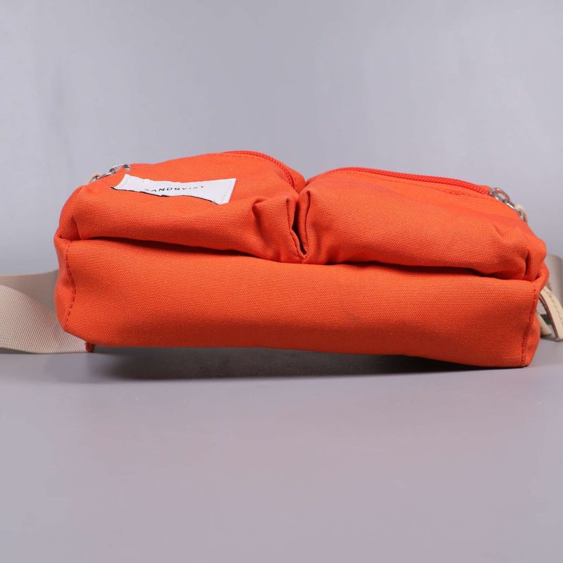 Botten av orange axelremsväska liggande på sidan