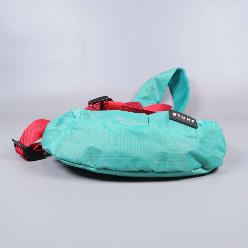 Botten av turkos axelremsväska med röd rem synlig