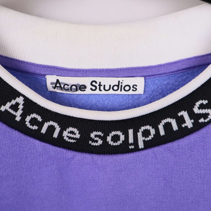 Närbild på logotypetikett Acne Studios i kragen