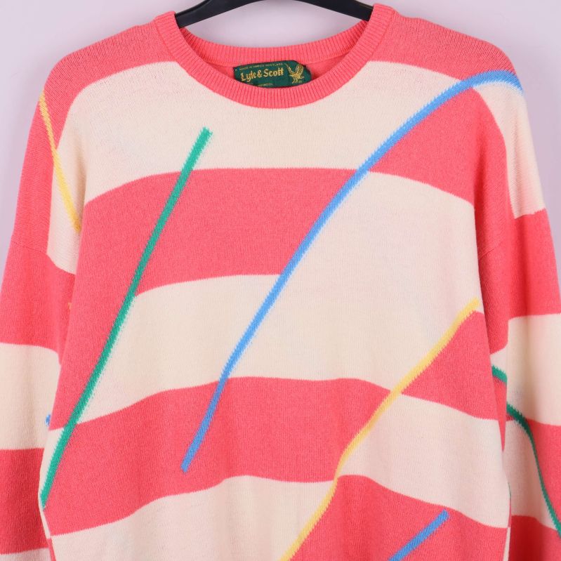 Närbild av tröjans liv med breda aprikosa och gräddvita ränder samt färgglada linjer