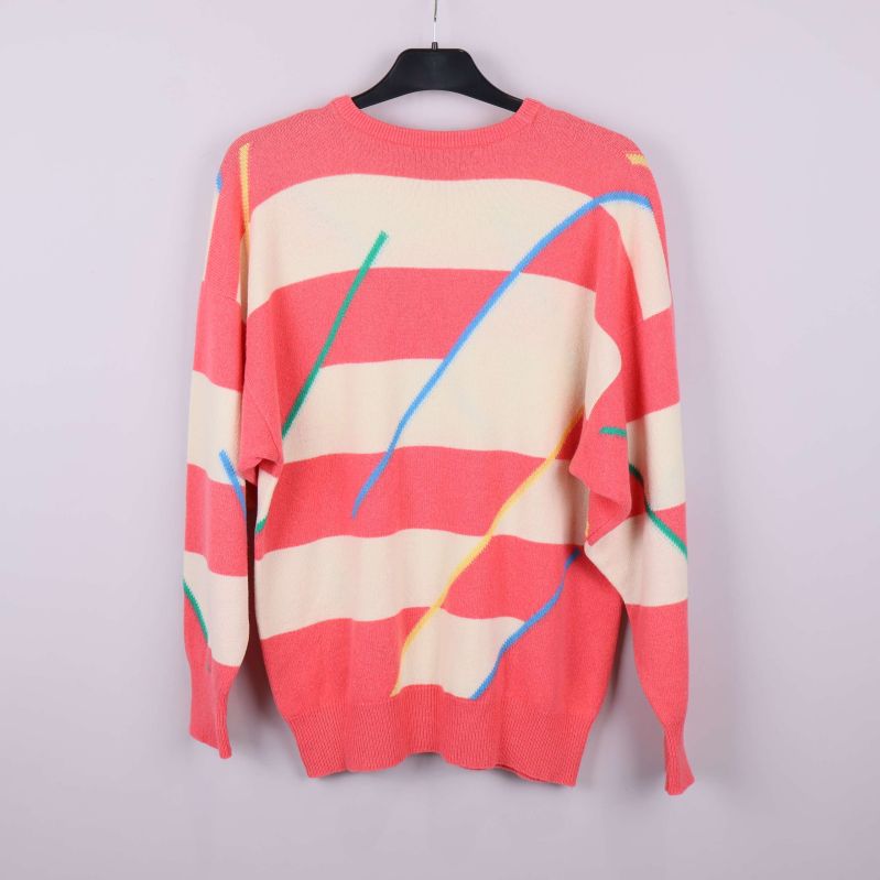 Baksidan av randig tröja i aprikos och gräddvit hänger på galge