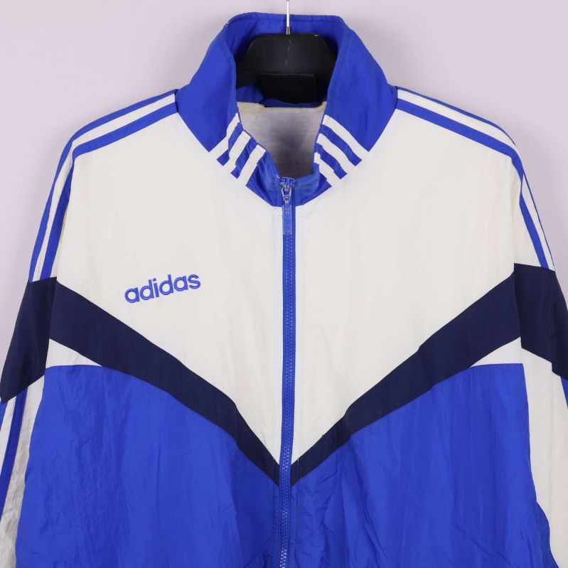 Närbild av överdelen på Adidas jacka med logotyp och mönster