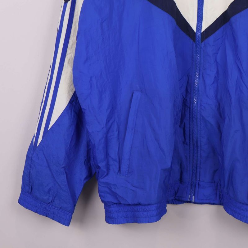 Närbild av nedre delen samt ficka på blåvit Adidas jacka