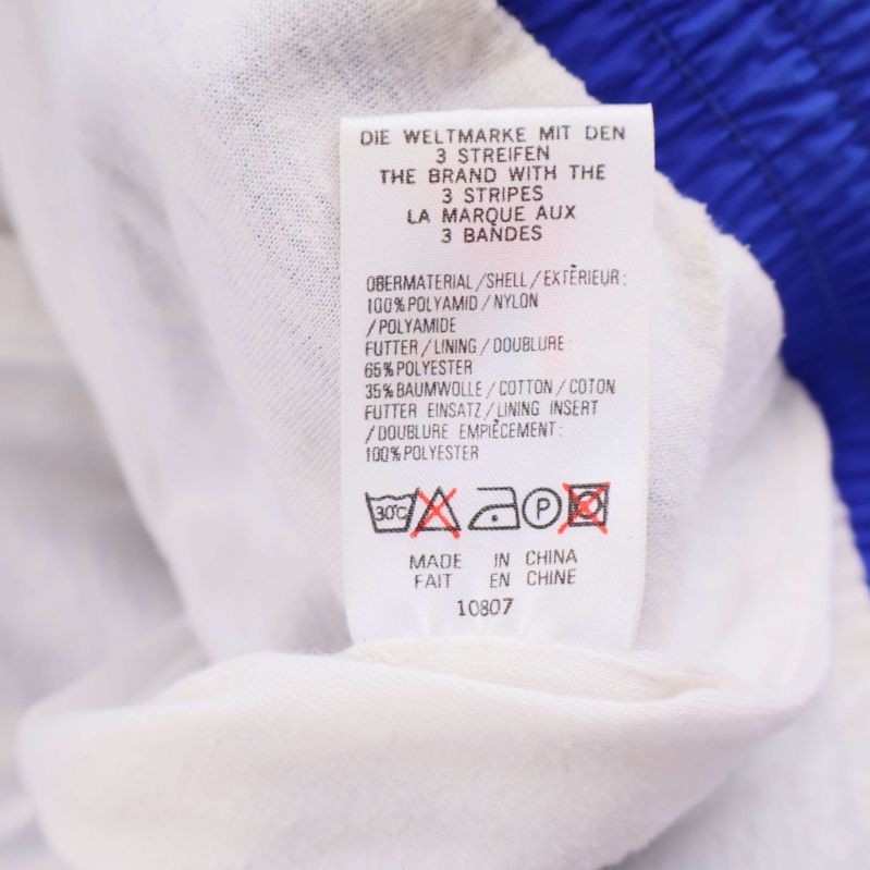 Material- och skötselråds-etikett inuti Adidas jacka