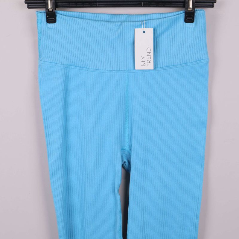 Närbild på midjan med etikett på blå ribbade leggings