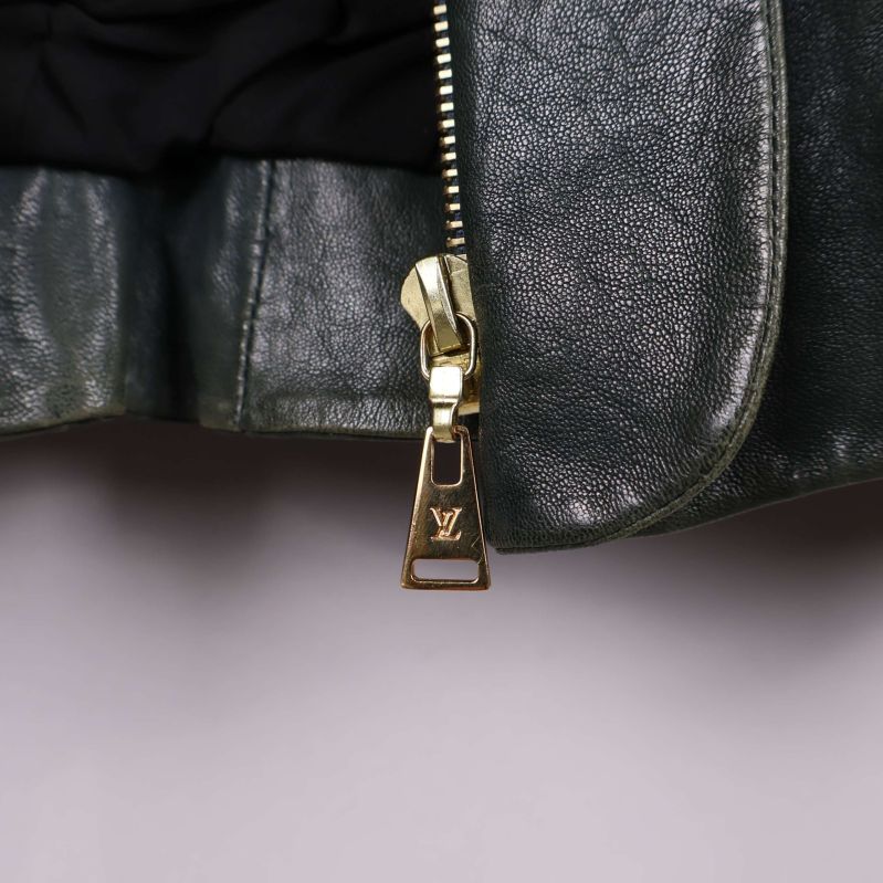 Detaljerad bild på guld dragkedja med LV-logo