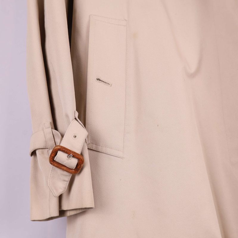 Detalj närbild på ärmslut och ficka med spänne på trenchcoat