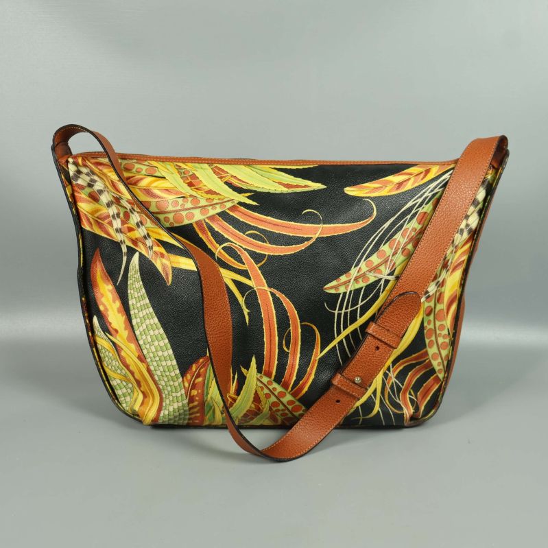 Baksidan av väska med färgglada växtmotiv och brun rem