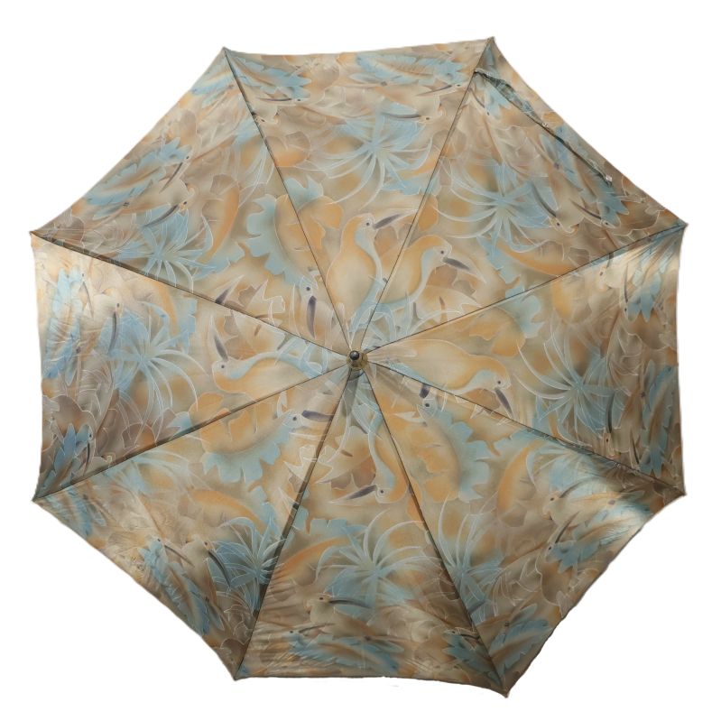 Paraplyet är utfällt med mönster av fåglar och blad