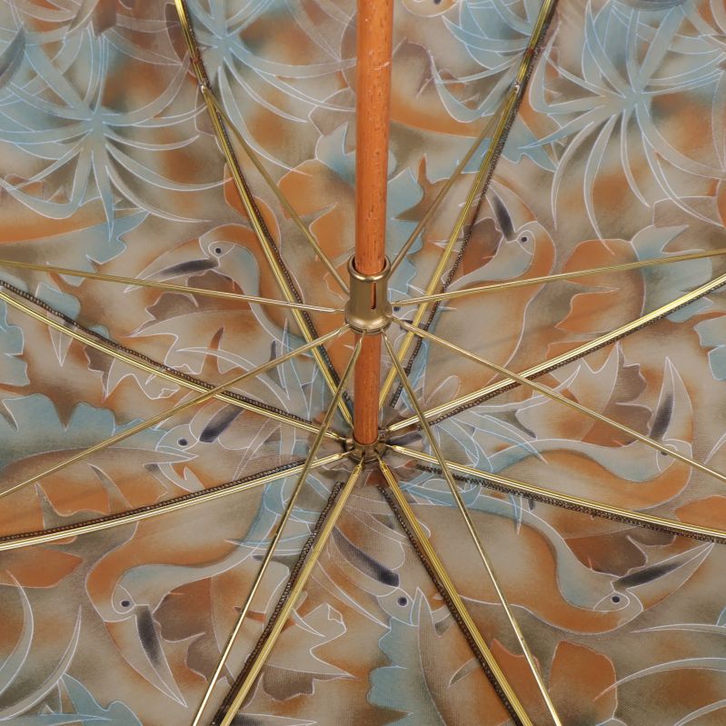 Insidan av paraplyet med mässingsfärgade ekrar och trästång