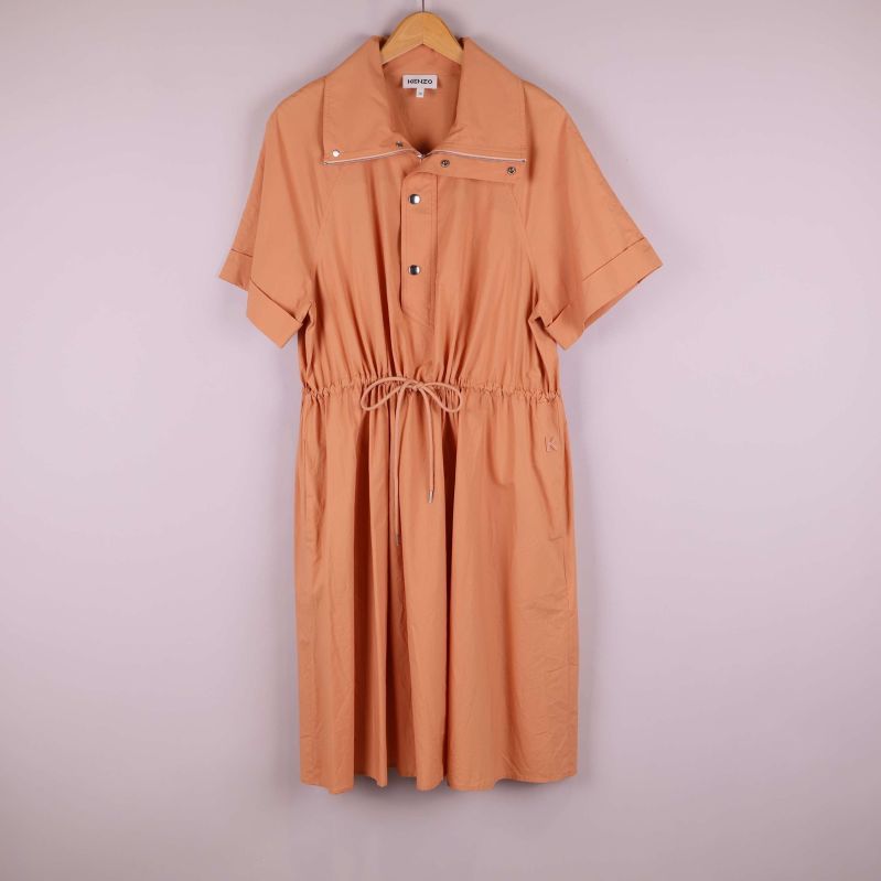 Aprikos klänning med kort ärm och dragsko hänger på en galge