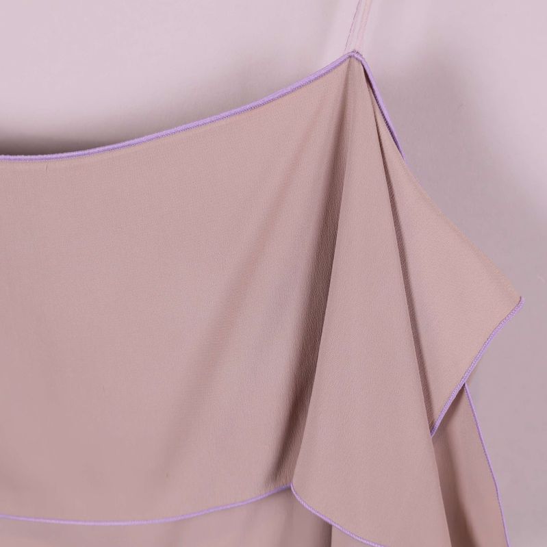 Närbild på axelband och volangkant med lila söm