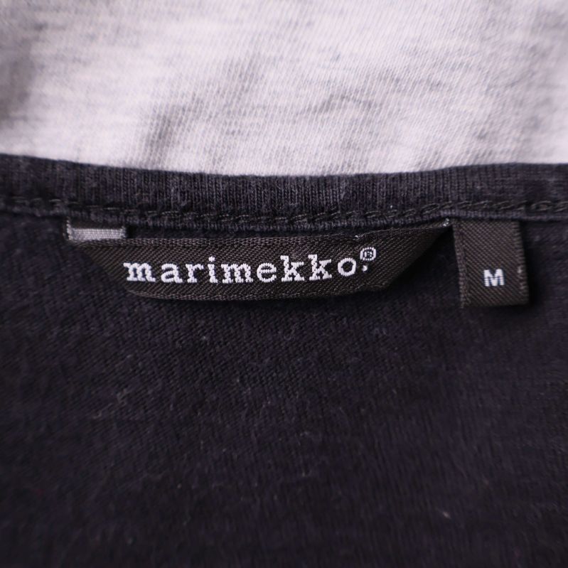 Närbild av Marimekko-loggan och storlekslapp i kragen