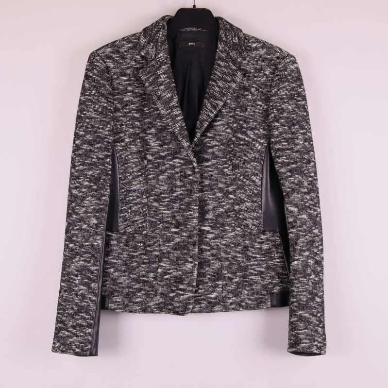 Kavaj i svart och grått mönster på galge mot ljus vägg