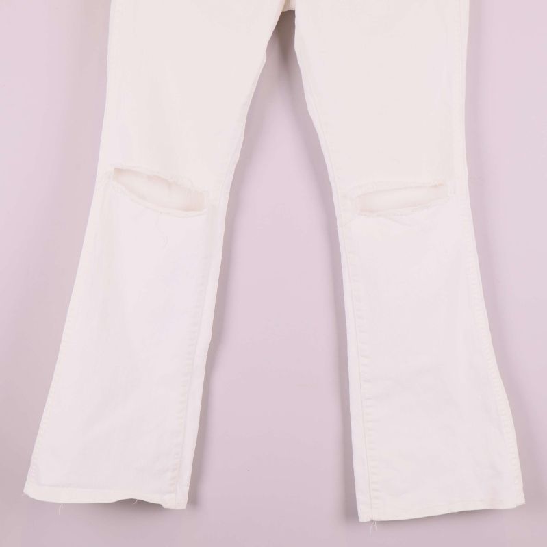 Slitna detaljer vid knäna på gräddvita jeans