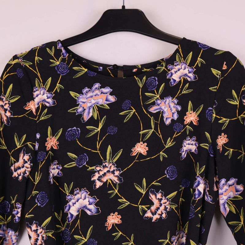 Närbild på halsringning och axlar med blommig design