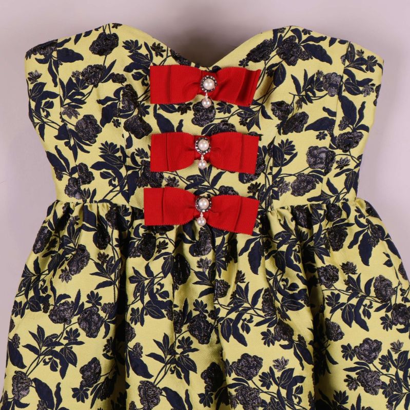 Överdel på klänning med tre röda rosetter och blommigt tyg