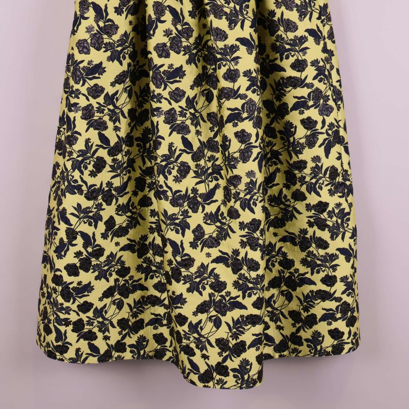 Blommigt tyg i marinblått på ljusgul bakgrund, närbild på kjolen