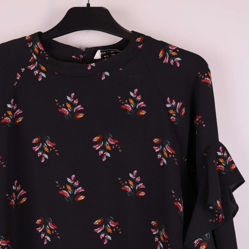 Närbild på klänningens överdel och blommigt mönster