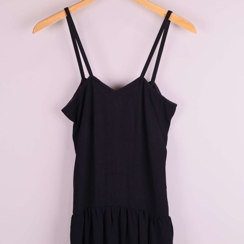 Detaljvy av överdelen med axelband på svart klänning