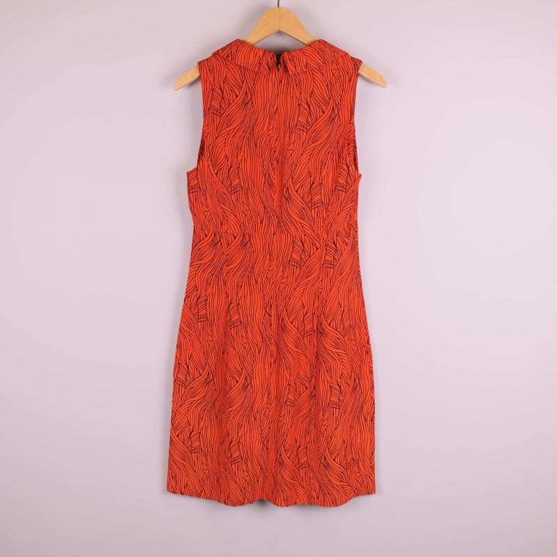 Baksida av orange mönstrad ärmlös klänning på galge