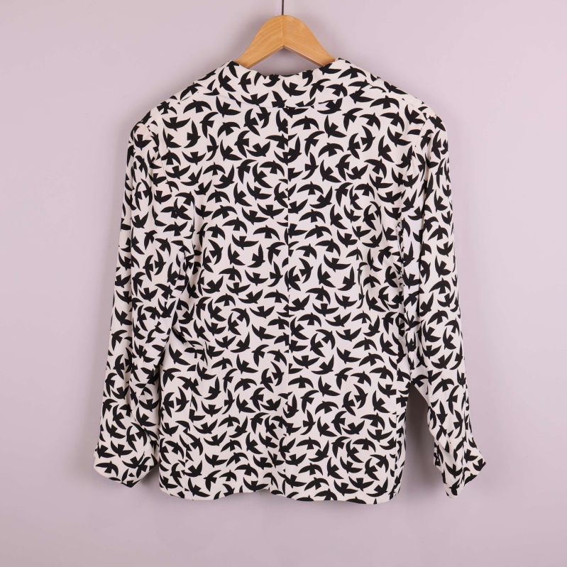 Kavaj med svart fågelmönster bakifrån på galge