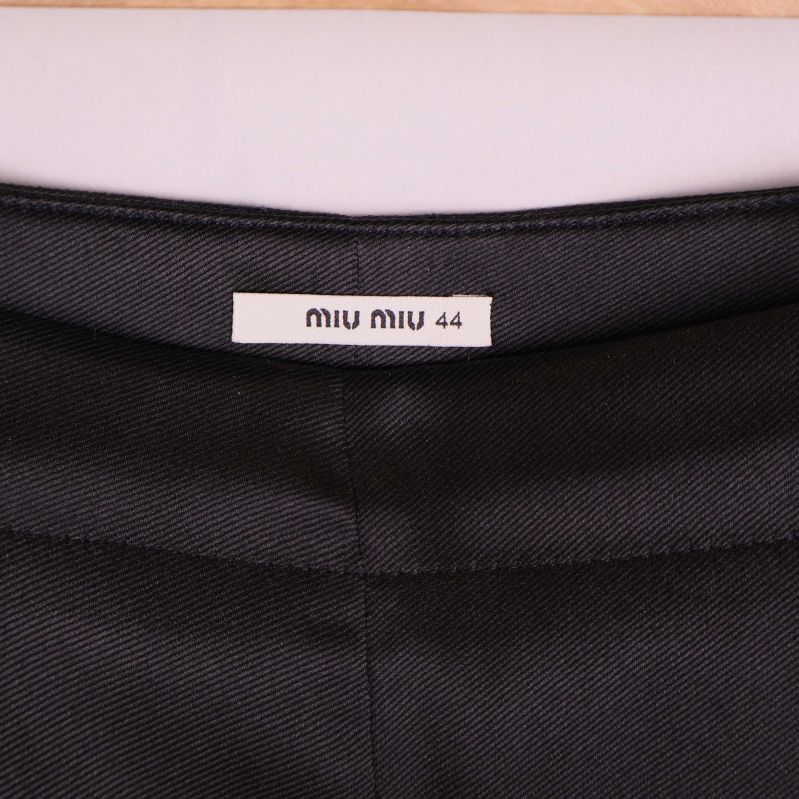 Närbild på Miu Miu-etikett i linningen på svarta byxor