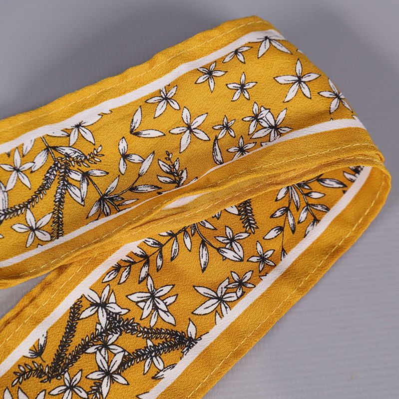 Närbild på gult hårband med vita blommor och vita kanter