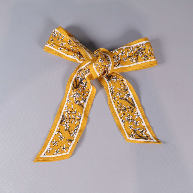 Gult hårband format till rosett med blommönster på grå bakgrund