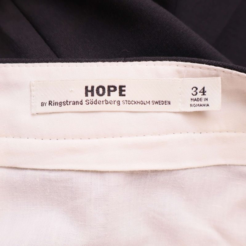 Närbild av vit etikett med HOPE och storlek 34 i midjan