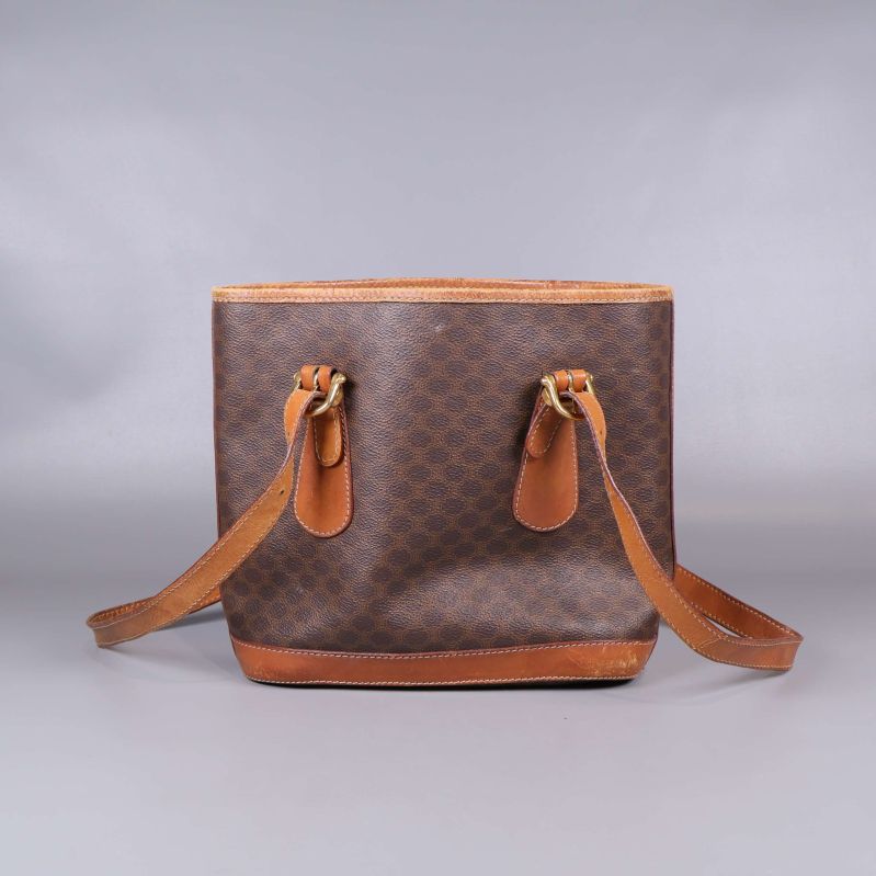 Baksida av brun toteväska med mönster och läderremmar