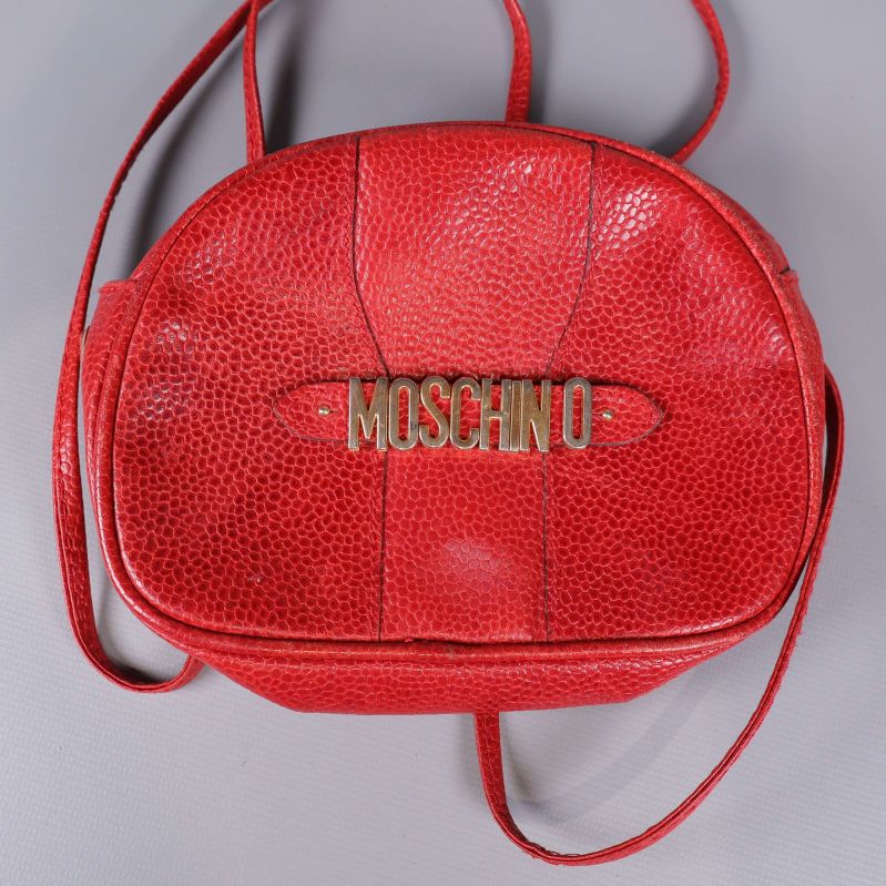 Framsida av röd Moschino-väska med guldfärgad logotyp