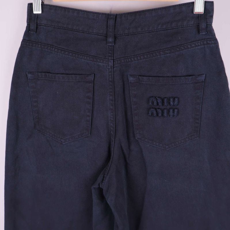 Närbild på bakfickor och broderad MIU MIU-logga