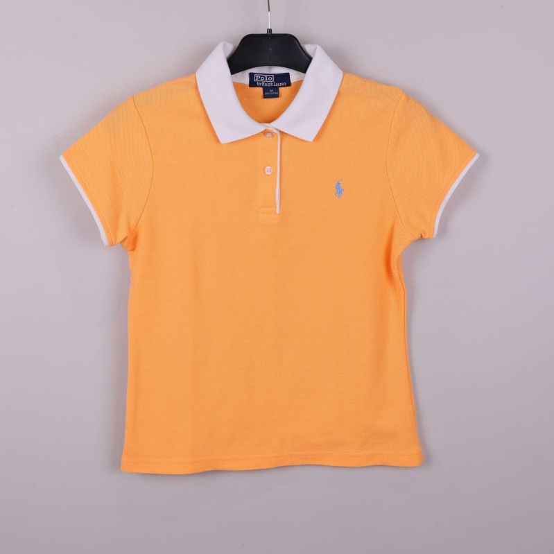 Aprikos pikétröja med vit krage hängande på galge framifrån