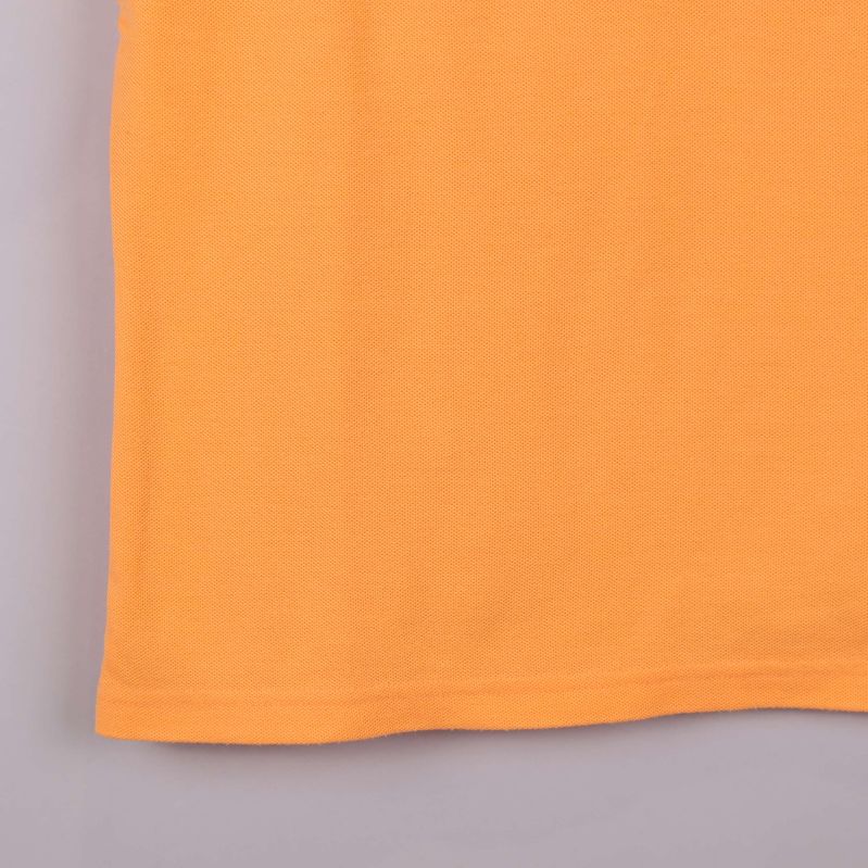 Närbild på nederkant av aprikos pikétröja