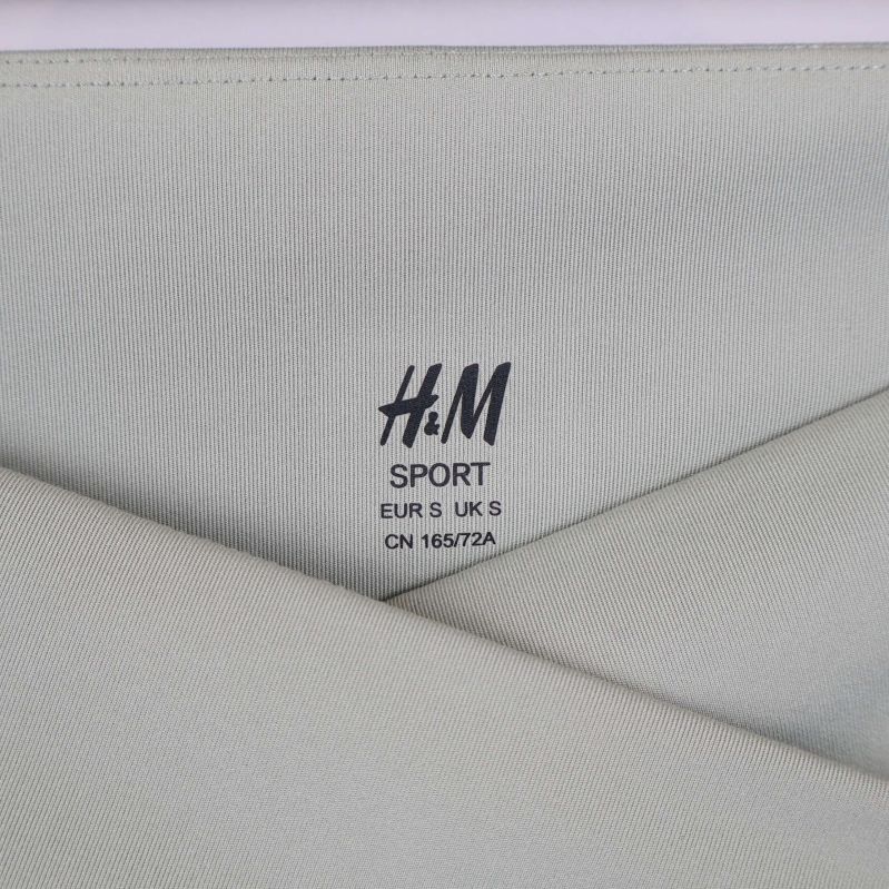 Närbild på h&m sport logga och korsad midjesöm