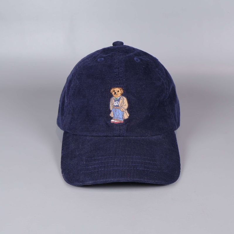 Framsidan av blå manchesterkeps med björnmotiv visas tydligt