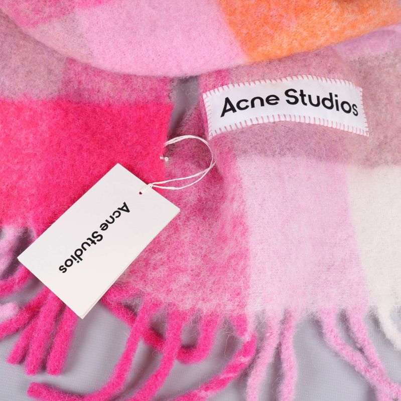 Närbild på Acne Studios-märke och etikett på färgrik halsduk