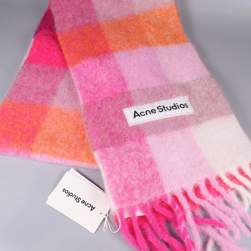 Närbild på rutigt mönster och fransar på halsduk i rosa och orange