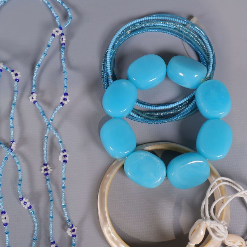 Närbild på blåa plastarmband och pärlarmband i olika nyanser