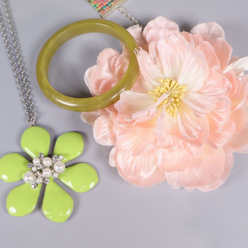 Grön armband och stor ljusrosa tygblomma i närbild