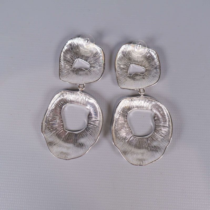 Baksidan av stora silvriga örhängen med texturerad yta