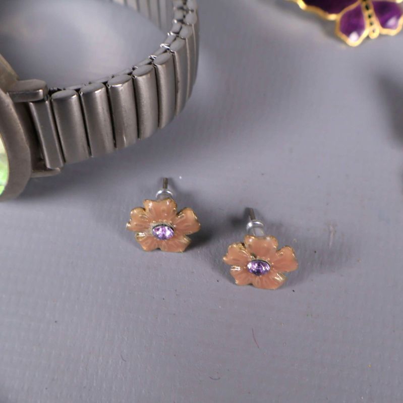 Små blomformade örhängen med lila sten i mitten